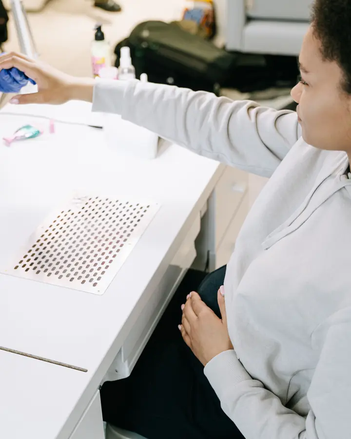 Technician in blue gloves working on a client manicure