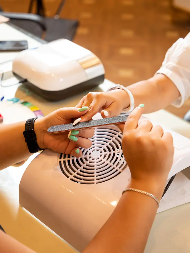 Technician filing a client's nails over a dust extractor
